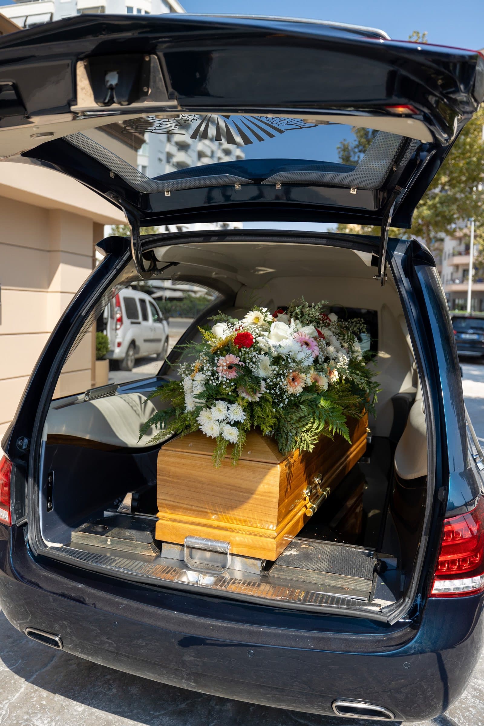 Automjeti funeral me derën e pasme të hapur, me arkivol dhe lule brenda.