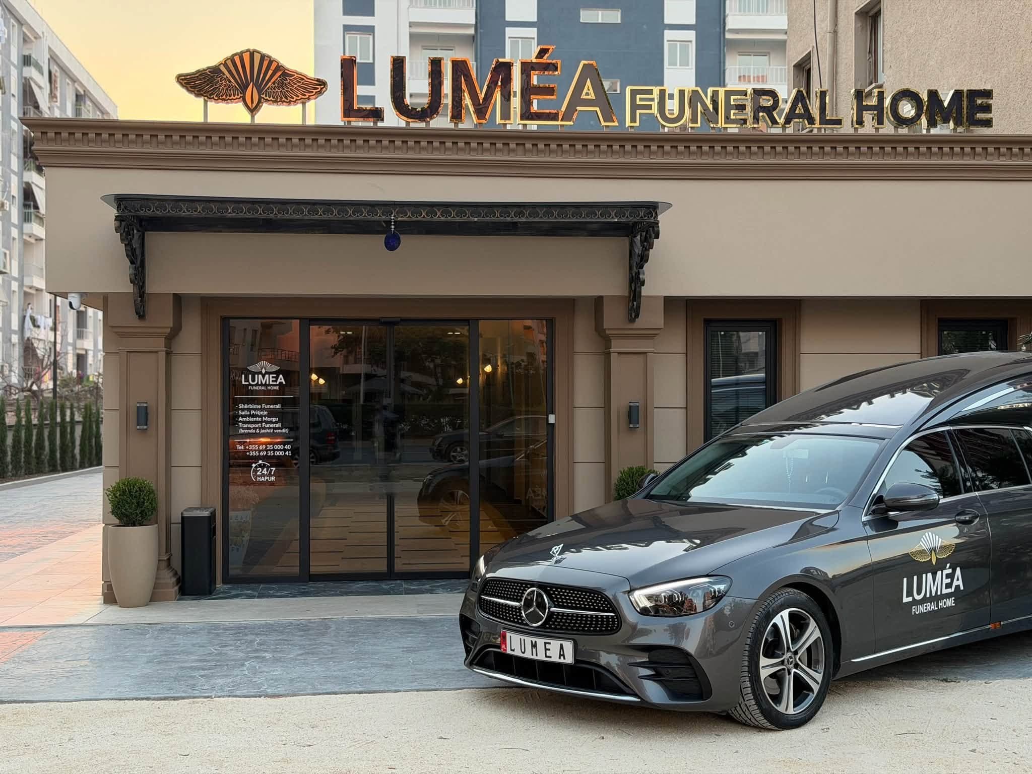 Tabela LUMÉA Funeral Home mbi hyrje dhe automjeti funeral përpara.